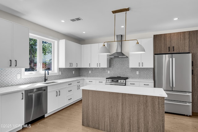 21 Pension Hill Rd, Manalapan, NJ 07726 - kitchen with appliances with stainless steel finishes, wall chimney range hood, a kitchen island, decorative backsplash, and white cabinetry