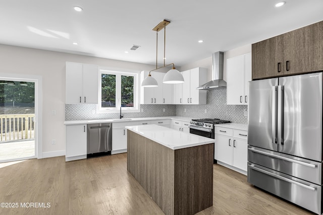 21 Pension Hill Rd, Manalapan, NJ 07726 - kitchen with stainless steel appliances, wall chimney range hood, light countertops, light wood finished floors, and decorative backsplash