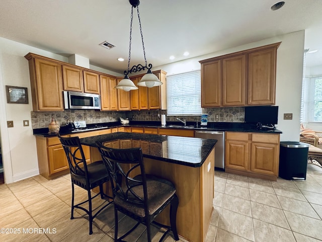 1642 Mink Ct, Toms River, NJ 08755 - kitchen featuring appliances with stainless steel finishes, tasteful backsplash, a center island, brown cabinets, and a breakfast bar