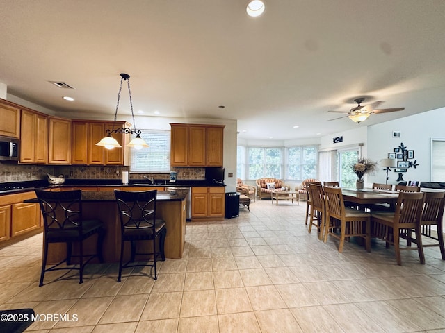 1642 Mink Ct, Toms River, NJ 08755 - kitchen featuring stainless steel appliances, dark countertops, backsplash, brown cabinets, and light tile patterned floors