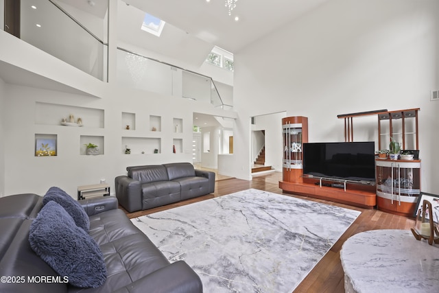 42 Nikki Ct, Morganville, NJ 07751 - living area with a towering ceiling, wood finished floors, a skylight, stairs, and built in features