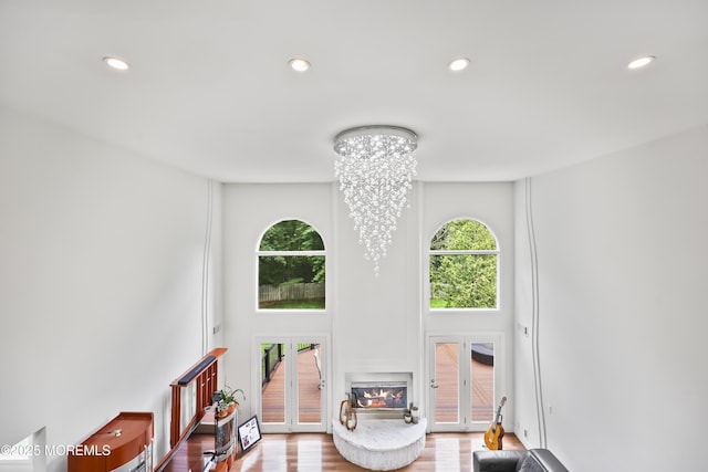 42 Nikki Ct, Morganville, NJ 07751 - living room with recessed lighting, a chandelier, a high ceiling, french doors, and a glass covered fireplace