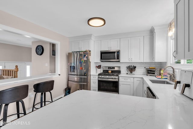 24 Willow Brook Rd, Freehold, NJ 07728 - kitchen featuring appliances with stainless steel finishes, light stone counters, backsplash, white cabinets, and a kitchen bar