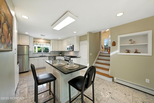 7 Stony Ridge Dr, Hillsdale, NJ 07642 - kitchen featuring a breakfast bar area, appliances with stainless steel finishes, dark countertops, white cabinets, and tasteful backsplash
