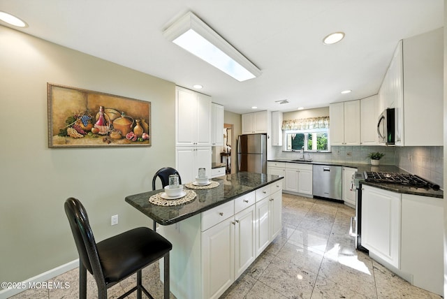 7 Stony Ridge Dr, Hillsdale, NJ 07642 - kitchen featuring appliances with stainless steel finishes, decorative backsplash, a breakfast bar area, white cabinets, and a center island