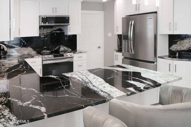 177 N Ensign Dr, Little Egg Harbor, NJ 08087 - kitchen featuring appliances with stainless steel finishes, backsplash, white cabinetry, dark stone countertops, and a kitchen bar