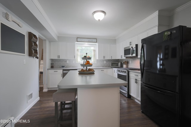 1113 Pemberton St, Toms River, NJ 08757 - kitchen with appliances with stainless steel finishes, a kitchen breakfast bar, backsplash, dark wood-type flooring, and crown molding