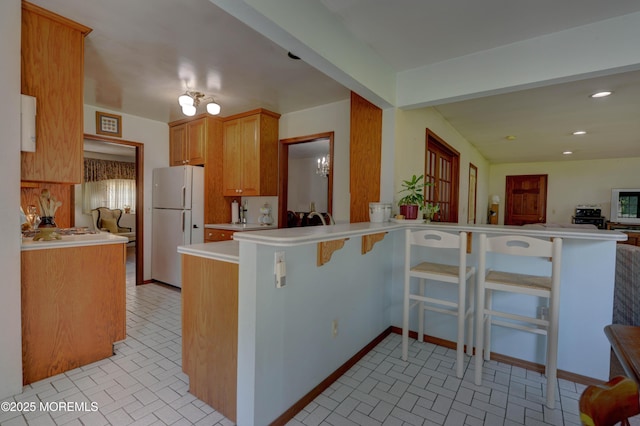 26 Old Manor Rd, Holmdel, NJ 07733 - kitchen with freestanding refrigerator, a peninsula, brick patterned flooring, light countertops, and recessed lighting