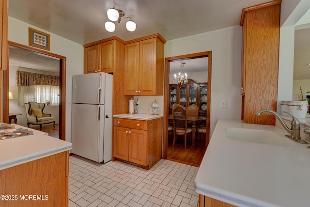 26 Old Manor Rd, Holmdel, NJ 07733 - kitchen featuring freestanding refrigerator, a chandelier, light countertops, brick patterned flooring, and brown cabinetry