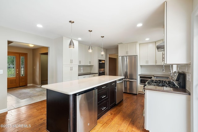 424 Continental St, Forked River, NJ 08731 - kitchen with appliances with stainless steel finishes, white cabinetry, light wood-style floors, a kitchen island, and backsplash