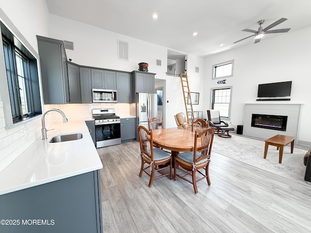 3365 Heron Ln, Lavallette, NJ 08735 - dining space featuring light wood-style floors, a glass covered fireplace, recessed lighting, ceiling fan, and a high ceiling