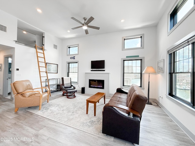 3365 Heron Ln, Lavallette, NJ 08735 - living area featuring light wood-style floors, a towering ceiling, a glass covered fireplace, ceiling fan, and recessed lighting