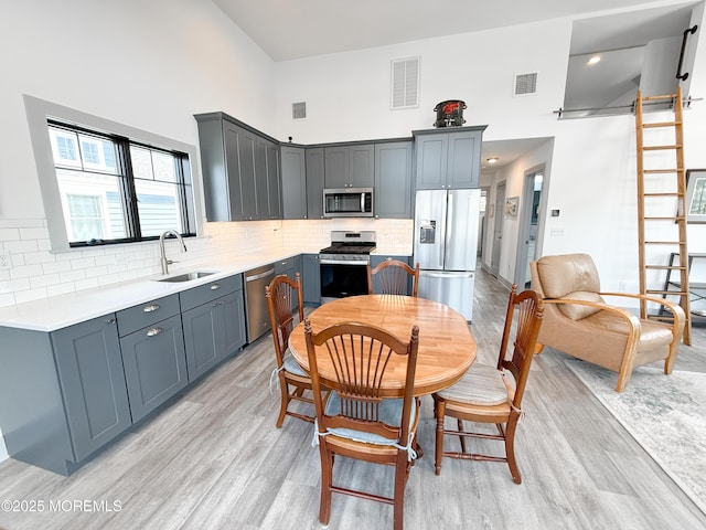 3365 Heron Ln, Lavallette, NJ 08735 - kitchen featuring stainless steel appliances, a high ceiling, light wood-style flooring, backsplash, and light countertops