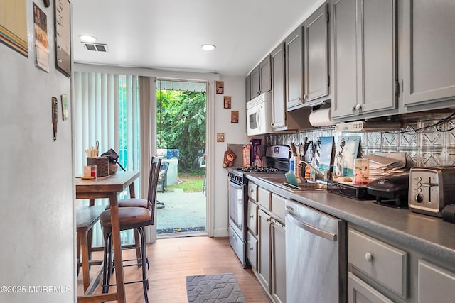 36 W Point Pleasant Ave, Ocean Gate, NJ 08740 - kitchen with appliances with stainless steel finishes, gray cabinets, light wood-style flooring, backsplash, and recessed lighting