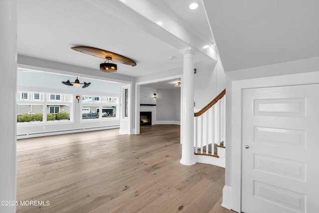 900 Ocean Ave, Bradley Beach, NJ 07720 - unfurnished living room featuring wood finished floors, a baseboard heating unit, stairway, a warm lit fireplace, and decorative columns