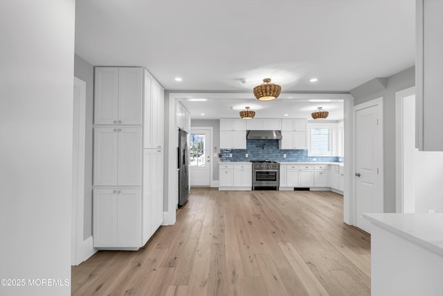900 Ocean Ave, Bradley Beach, NJ 07720 - kitchen with stainless steel appliances, under cabinet range hood, light wood finished floors, white cabinetry, and decorative backsplash