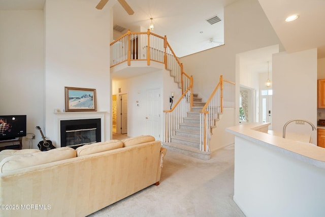 98 Mirage Blvd, Barnegat, NJ 08005 - living room featuring ceiling fan, a towering ceiling, stairway, light carpet, and a glass covered fireplace