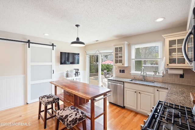 15 Tanglewood Dr, Barnegat, NJ 08005 - kitchen with a textured ceiling, a barn door, light wood finished floors, appliances with stainless steel finishes, and wainscoting