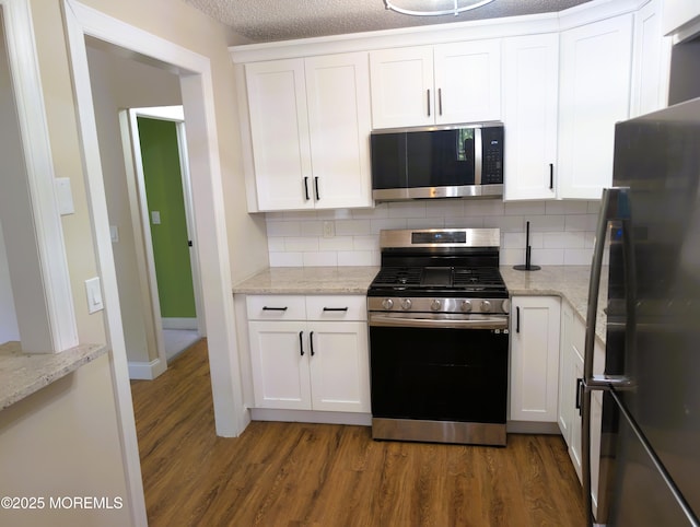 101 Begonia Ct, Jackson, NJ 08527 - kitchen with appliances with stainless steel finishes, wood finished floors, tasteful backsplash, white cabinets, and light stone counters