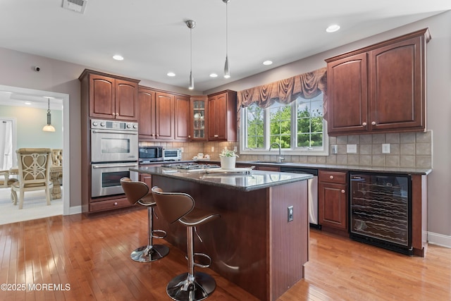 1 Hopkinson Ct, Marlboro, NJ 07746 - kitchen featuring beverage cooler, appliances with stainless steel finishes, light wood-type flooring, decorative light fixtures, and a center island