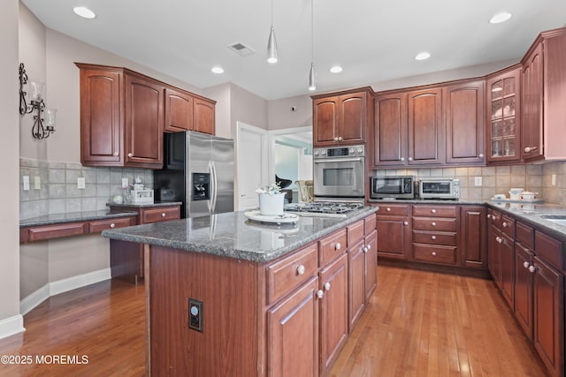 1 Hopkinson Ct, Marlboro, NJ 07746 - kitchen featuring stainless steel appliances, a kitchen island, light wood-type flooring, dark stone counters, and tasteful backsplash