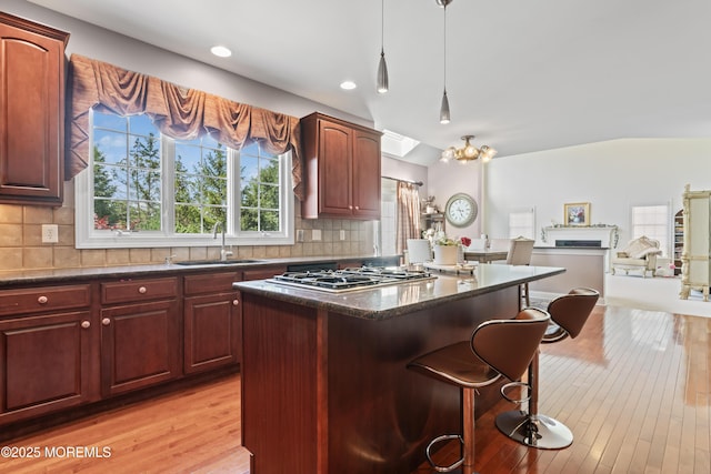 1 Hopkinson Ct, Marlboro, NJ 07746 - kitchen featuring stainless steel gas stovetop, a kitchen breakfast bar, a center island, light wood finished floors, and backsplash