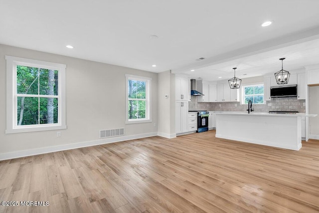 629 Monmouth Ave, Toms River, NJ 08757 - kitchen with stainless steel stove, wall chimney range hood, light countertops, open floor plan, and recessed lighting