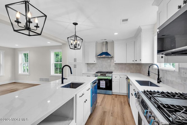 629 Monmouth Ave, Toms River, NJ 08757 - kitchen with appliances with stainless steel finishes, wall chimney range hood, a chandelier, light wood finished floors, and white cabinetry