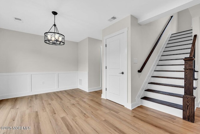 629 Monmouth Ave, Toms River, NJ 08757 - unfurnished dining area featuring light wood-style floors, stairs, a wainscoted wall, and a chandelier