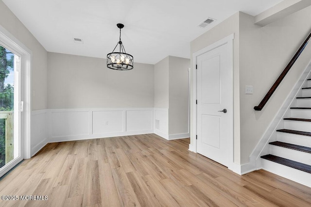 629 Monmouth Ave, Toms River, NJ 08757 - unfurnished dining area featuring light wood-type flooring, a chandelier, stairs, and wainscoting