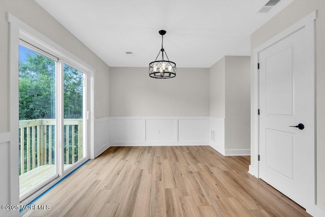 629 Monmouth Ave, Toms River, NJ 08757 - unfurnished dining area featuring light wood finished floors, a chandelier, and a wainscoted wall