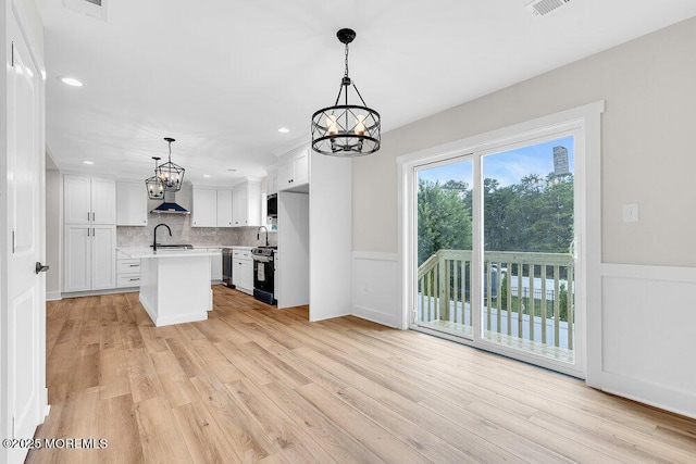 629 Monmouth Ave, Toms River, NJ 08757 - kitchen featuring a chandelier, light countertops, appliances with stainless steel finishes, white cabinetry, and a wainscoted wall