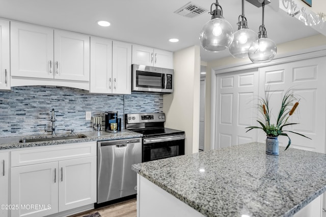 2108 SE Central Ave Unit 10, South Seaside Park, NJ 08752 - kitchen with appliances with stainless steel finishes, white cabinetry, light stone counters, a center island, and backsplash