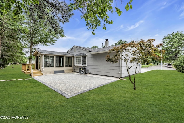 925 Edgebrook Dr N, Toms River, NJ 08757 - rear view of house featuring a sunroom, a chimney, a patio, a lawn, and roof with shingles
