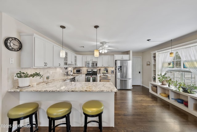 1587 Fort St, Brick, NJ 08724 - kitchen featuring stainless steel appliances, a peninsula, light stone counters, glass insert cabinets, and white cabinetry