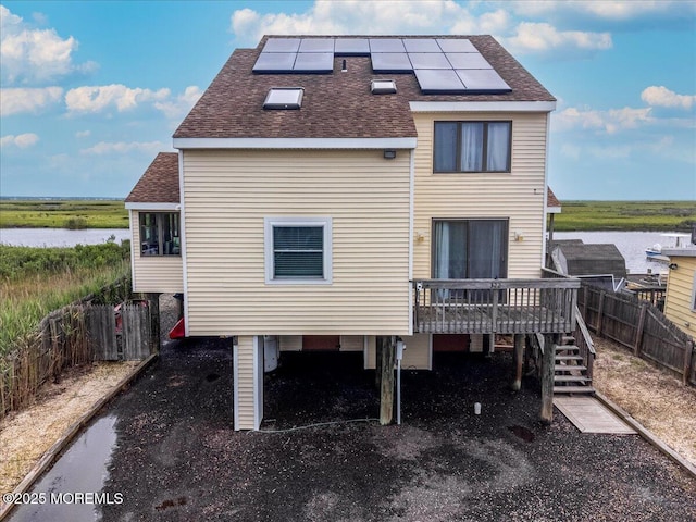 322 Dock Rd, West Creek, NJ 08092 - rear view of property with roof with shingles, roof mounted solar panels, a deck with water view, and stairway