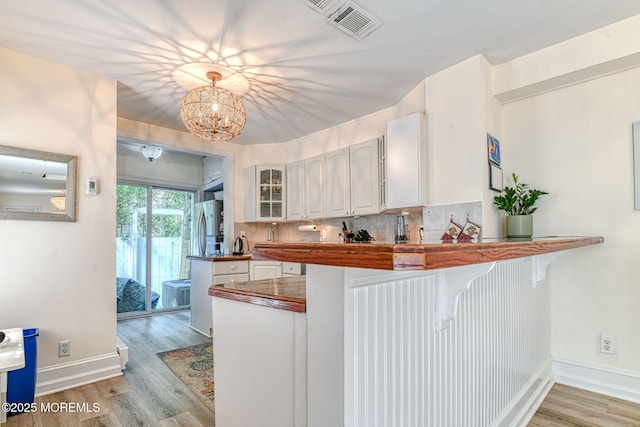 132 Heck Ave, Ocean Grove, NJ 07756 - kitchen featuring backsplash, glass insert cabinets, light wood finished floors, white cabinetry, and a chandelier