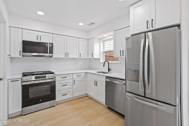 256 Greenwood Loop Rd, Brick, NJ 08724 - kitchen featuring appliances with stainless steel finishes, white cabinetry, light countertops, tasteful backsplash, and light wood-style floors