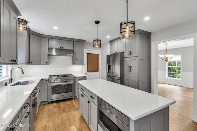 1207 Bayberry Rd, Manasquan, NJ 08736 - kitchen with high end appliances, gray cabinetry, under cabinet range hood, light wood-style flooring, and light countertops