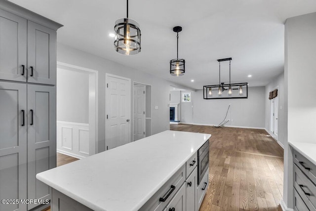 1207 Bayberry Rd, Manasquan, NJ 08736 - kitchen with gray cabinetry, light countertops, wood finished floors, stainless steel microwave, and pendant lighting