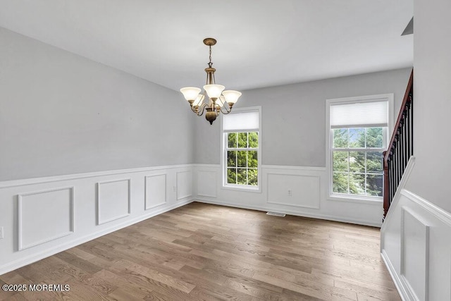 1207 Bayberry Rd, Manasquan, NJ 08736 - unfurnished room with a chandelier, a wainscoted wall, wood finished floors, a decorative wall, and stairs
