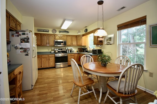 2 Dowing Ln, Jackson, NJ 08527 - kitchen featuring appliances with stainless steel finishes, dark countertops, light wood finished floors, hanging light fixtures, and brown cabinetry