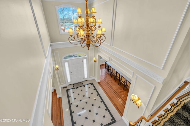 208 Imperial Ct, Lakewood, NJ 08701 - tiled entrance foyer featuring inlaid floor details, a chandelier, a high ceiling, and a decorative wall