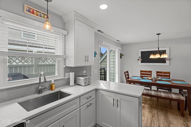 1301 SW Central Ave Unit A3, Seaside Park, NJ 08752 - kitchen featuring decorative backsplash, a peninsula, wood finished floors, white cabinetry, and a chandelier
