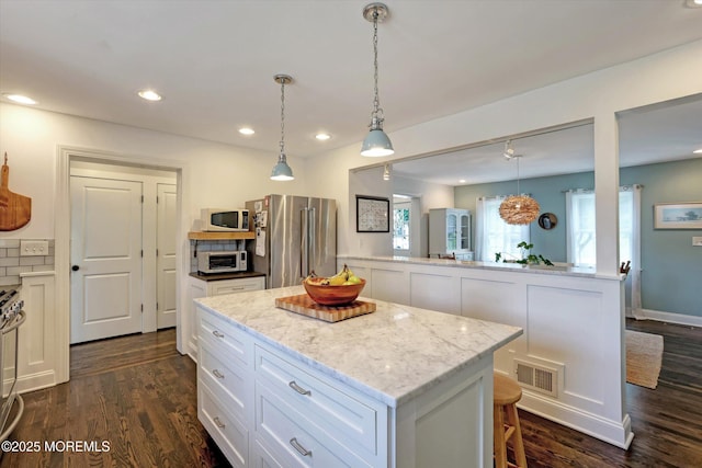 708 Lyman Ave, Brielle, NJ 08730 - kitchen featuring stainless steel appliances, a center island, white cabinetry, dark wood finished floors, and light stone counters