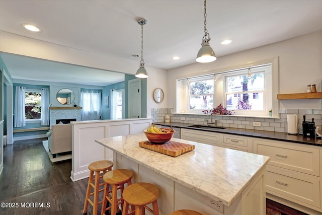 708 Lyman Ave, Brielle, NJ 08730 - kitchen featuring decorative backsplash, open floor plan, dark wood finished floors, a fireplace, and dark stone countertops