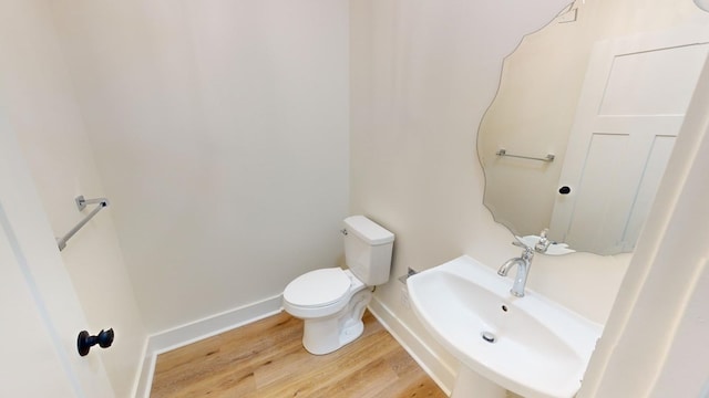 bathroom with wood-type flooring, toilet, and sink