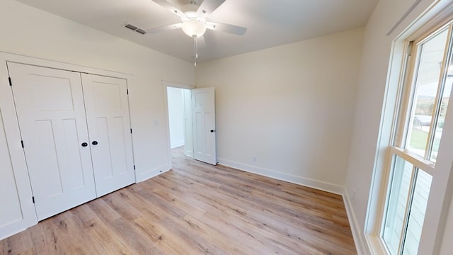 unfurnished bedroom with ceiling fan, light wood-type flooring, and a closet