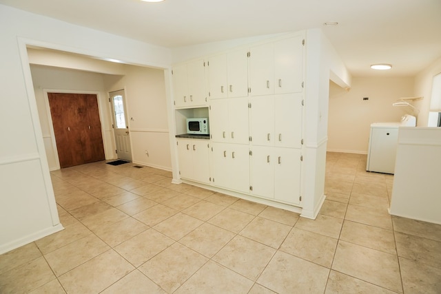 interior space with light tile patterned flooring, baseboards, white cabinets, and white microwave