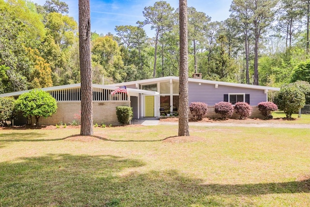mid-century modern home with a chimney and a front yard